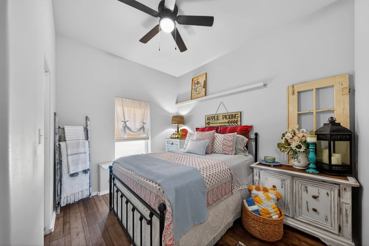 Guest bedroom with black iron bed frame, farmhouse decor, and wood-look flooring, barndominium Chandler TX
