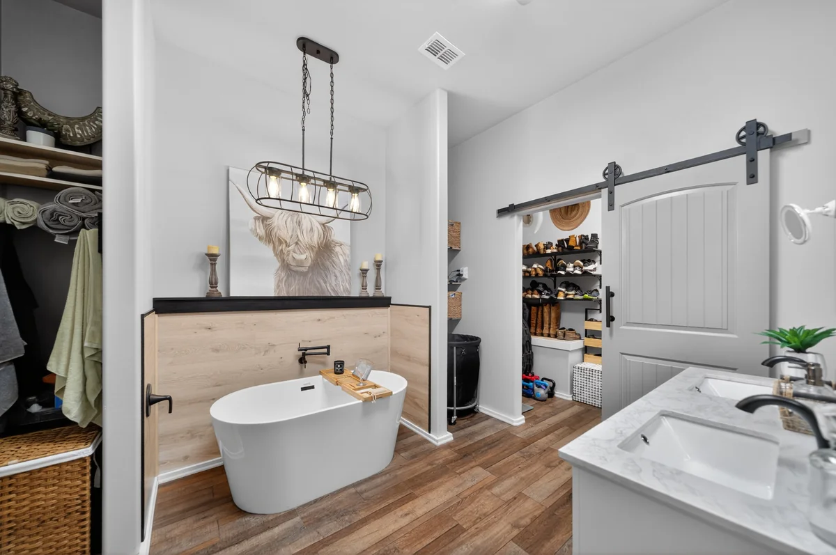Spa primary bathroom with freestanding soaking tub, wood plank niche, and cage pendant light, barndominium Chandler TX