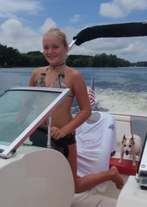 Young girl driving a boat on Lake Palestine East Texas with a dog on board with adult supervision