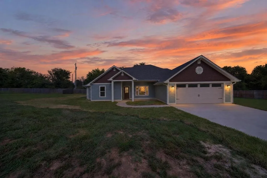 Front of 281 ACR 308 at dusk with the porch and garage lights on.