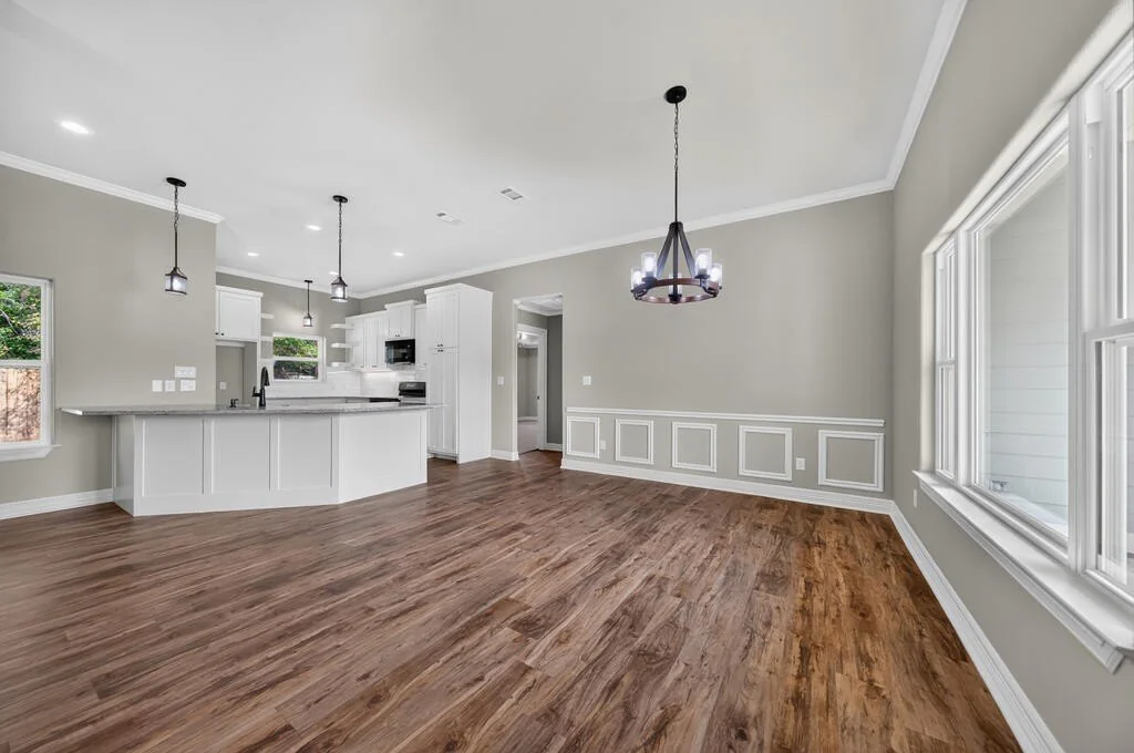 Dining area with a round iron chandelier and wall paneling, open to the kitchen at 281 ACR 308.