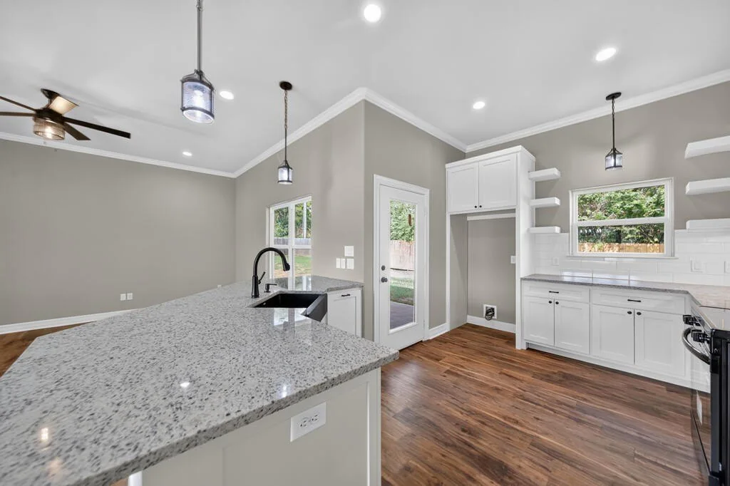 Kitchen with open floating shelves, a window over the counter and a glass rear door at 281 ACR 308.