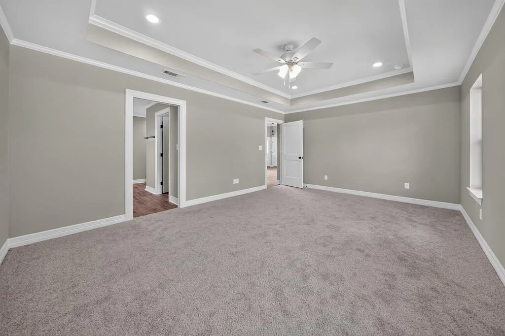 Primary bedroom with a tray ceiling and ceiling fan, with the doorway to the primary bath, at 281 ACR 308.