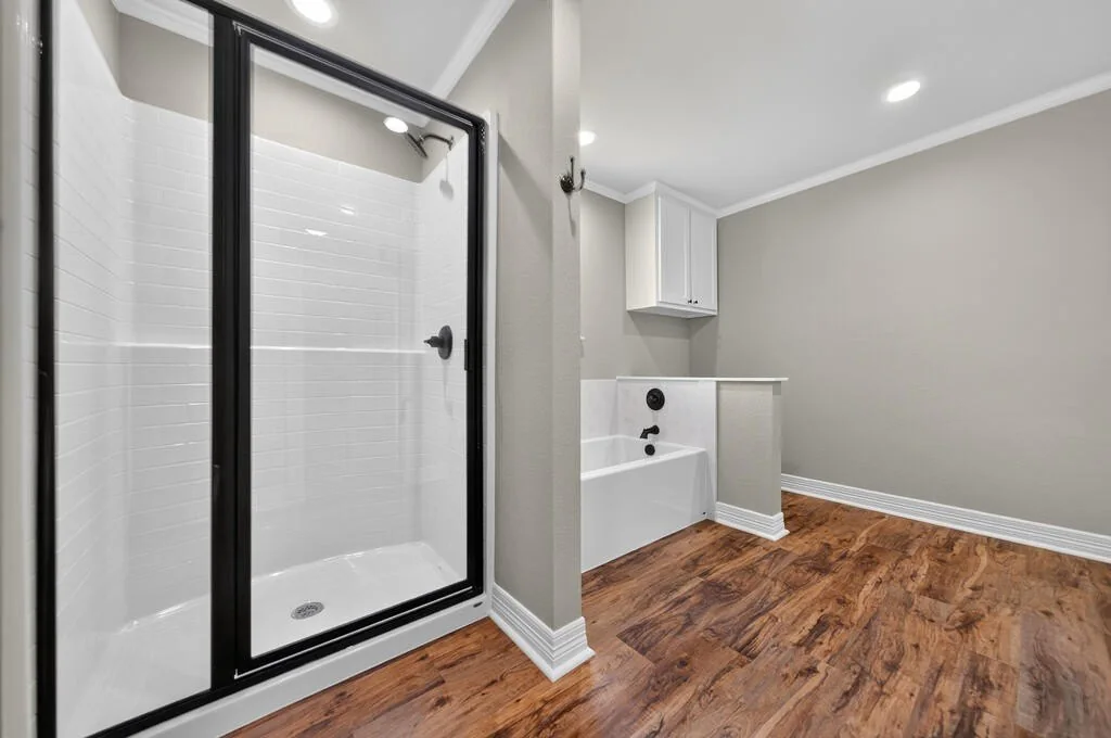 Walk-in shower with a black-framed glass door, with the tub beyond, at 281 ACR 308.