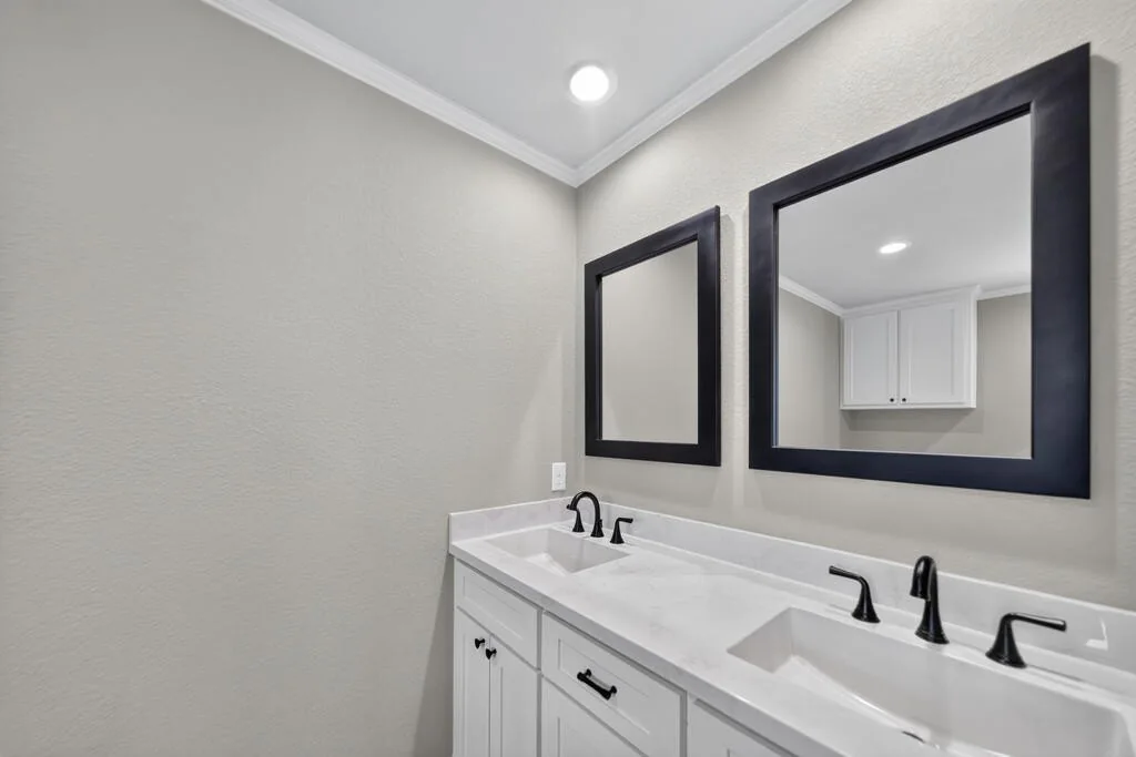Double-sink vanity with black-framed mirrors and black fixtures at 281 ACR 308.