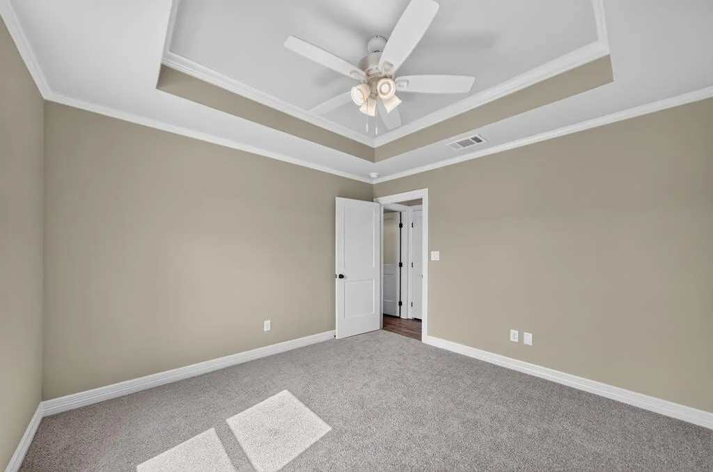 Carpeted bedroom with a tray ceiling and ceiling fan at 281 ACR 308.