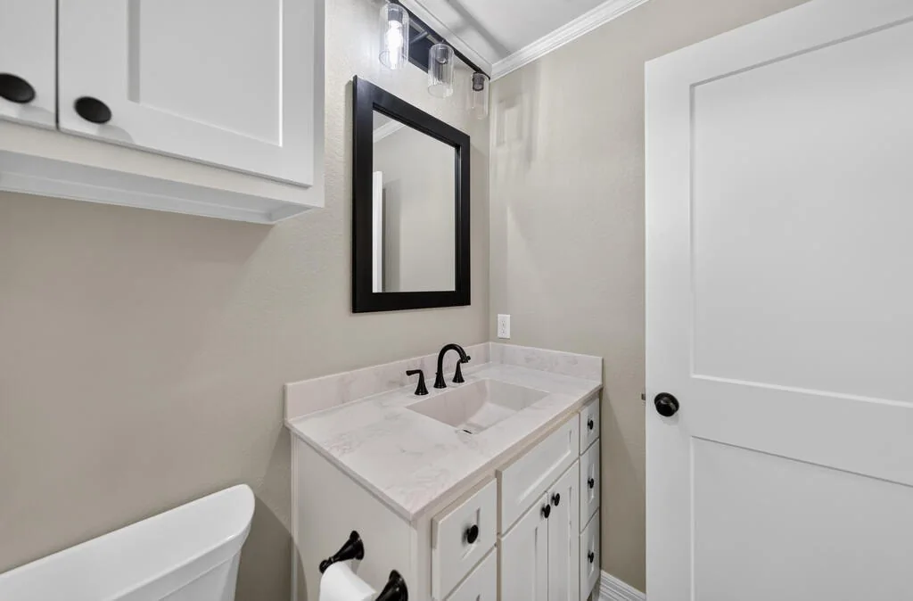 Bathroom vanity with a black-framed mirror and black fixtures at 281 ACR 308.