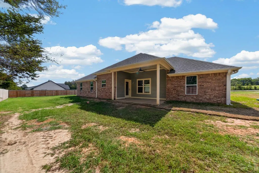 Back of 281 ACR 308 from the yard, showing the covered porch and brick exterior.