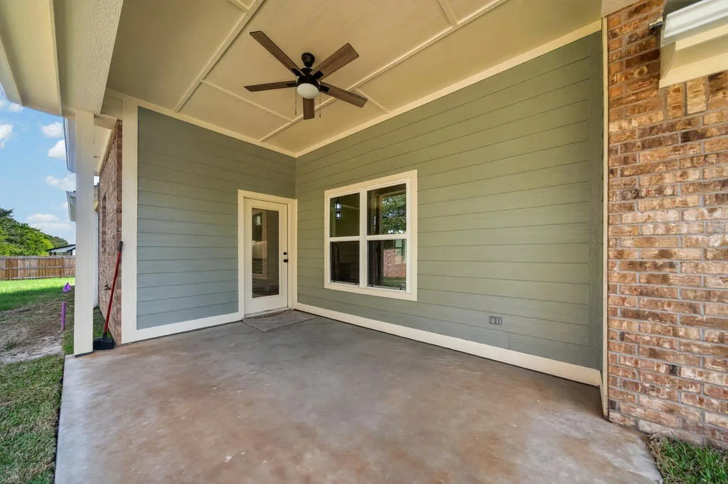 Covered back porch with a ceiling fan and the rear door at 281 ACR 308.