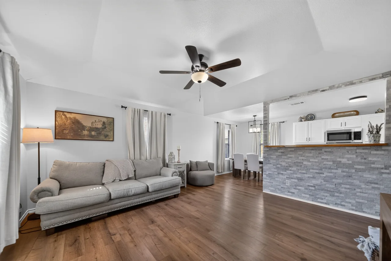Living room with wood-look floors and a stone-faced breakfast bar opening to the kitchen at 1054 Caroline Ln in Shadybrook, a gated Lake Palestine community in Bullard, TX.