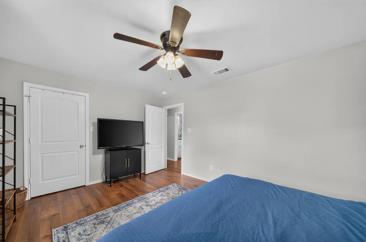 Primary bedroom with a ceiling fan and closet door at 1054 Caroline Ln in Shadybrook, a gated Lake Palestine community in Bullard, TX.
