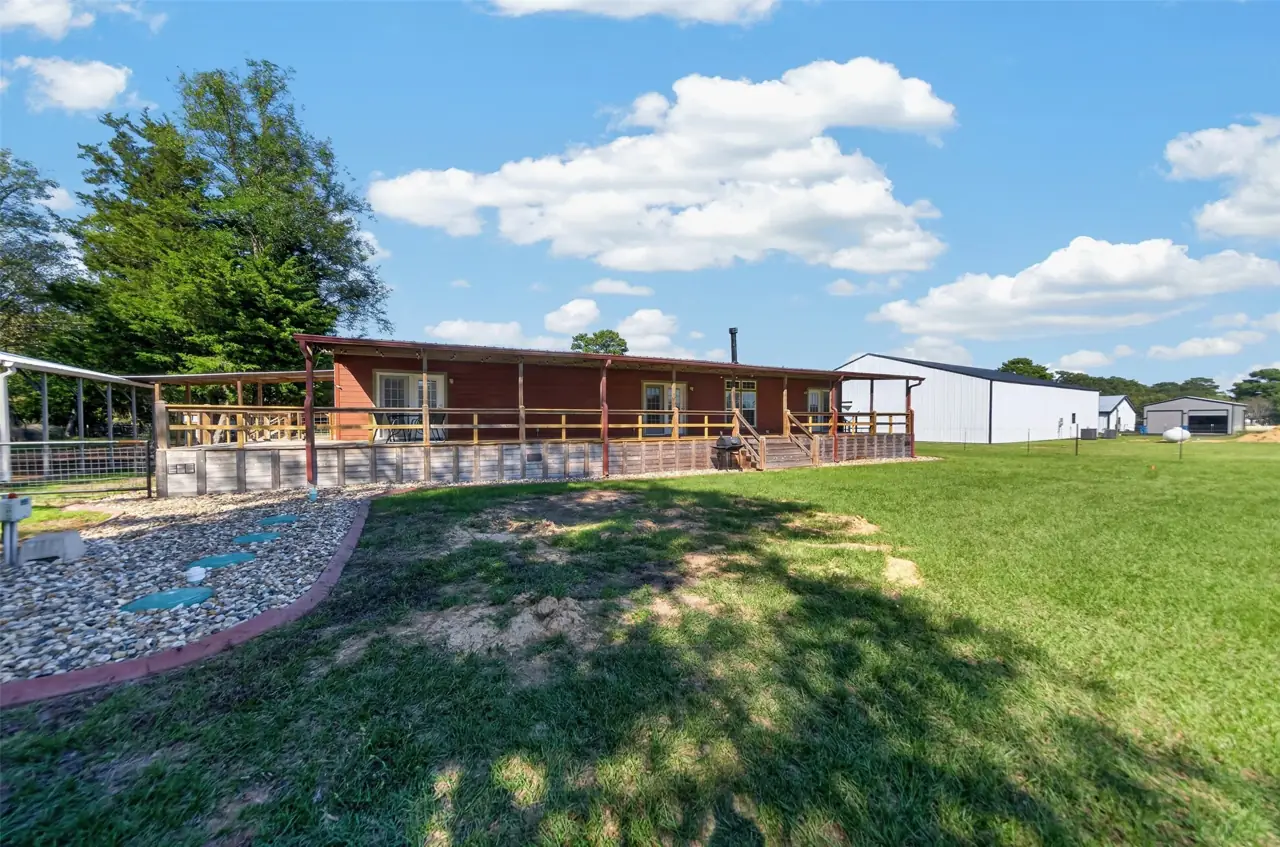 Rear deck seen from the yard, with rock landscaping along the foundation at 21138 County Road 4202 in Chandler, TX, across from Brown's Landing on Lake Palestine.