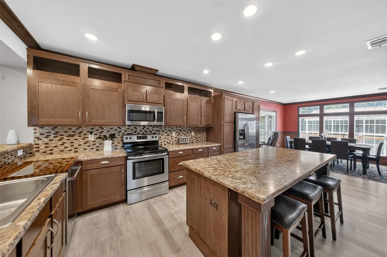 Kitchen with a large island, stainless appliances and tile backsplash, open to the dining area at 21138 County Road 4202 in Chandler, TX, across from Brown's Landing on Lake Palestine.