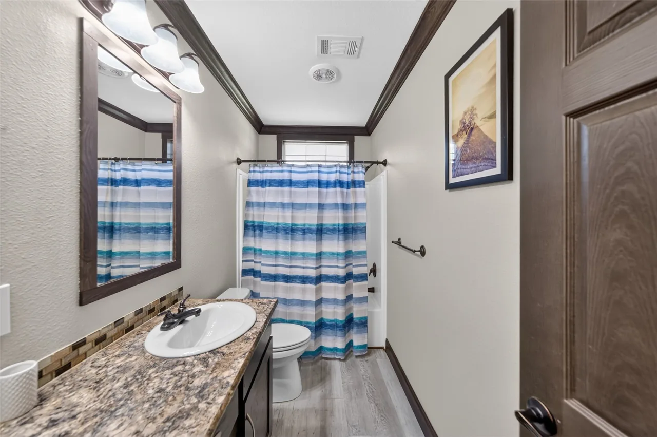 Hall bathroom with vanity and tub with shower at 21138 County Road 4202 in Chandler, TX, across from Brown's Landing on Lake Palestine.