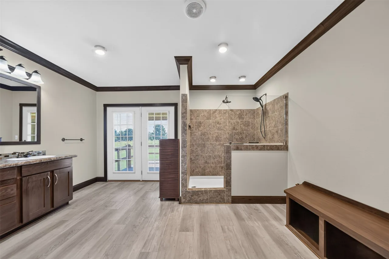 Primary bathroom with a walk-in shower, vanity and French doors at 21138 County Road 4202 in Chandler, TX, across from Brown's Landing on Lake Palestine.