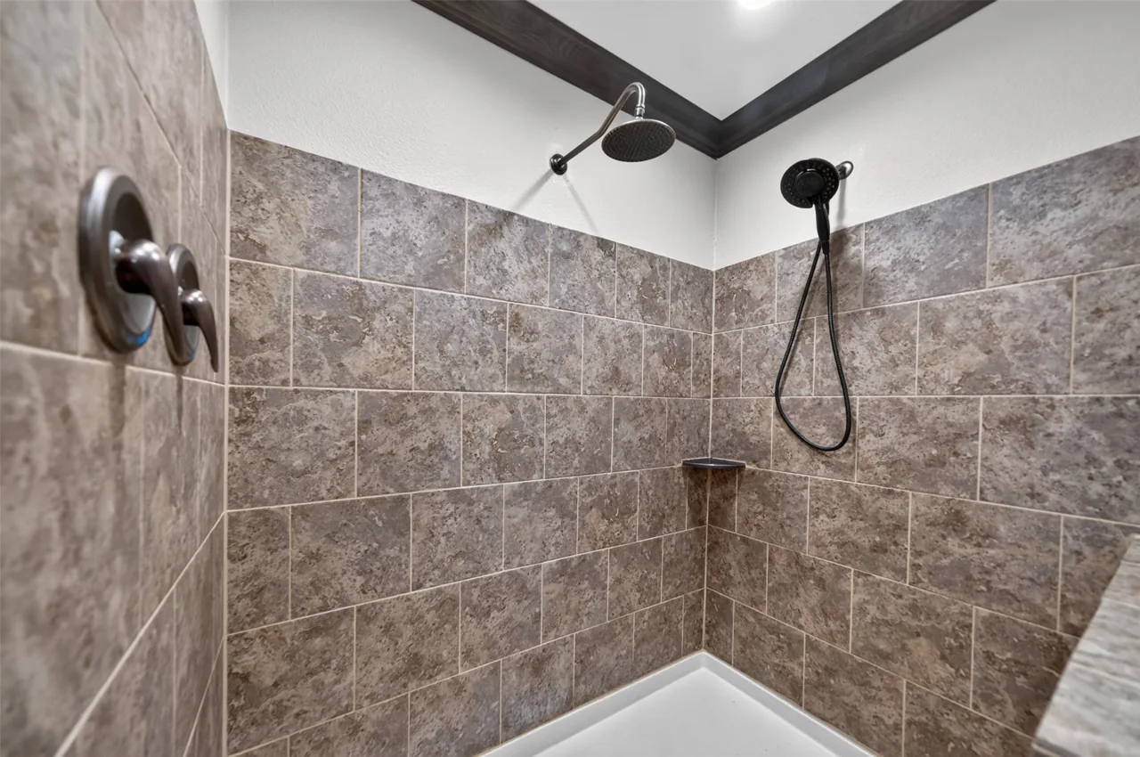 Tiled walk-in shower with a rain head and handheld sprayer in the primary bathroom at 21138 County Road 4202 in Chandler, TX, across from Brown's Landing on Lake Palestine.