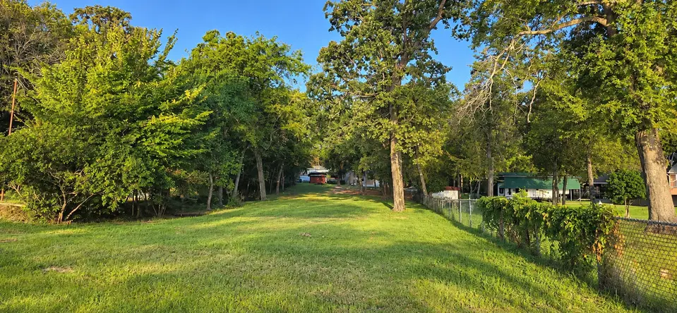 Wide view of the waterfront lot at 22693 Creekwood Dr from near the water, looking toward the street in Lakeway Harbor.
