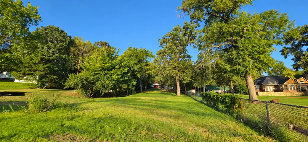 The lot at 22693 Creekwood Dr seen from the lake end, with the neighboring fence line on the right.