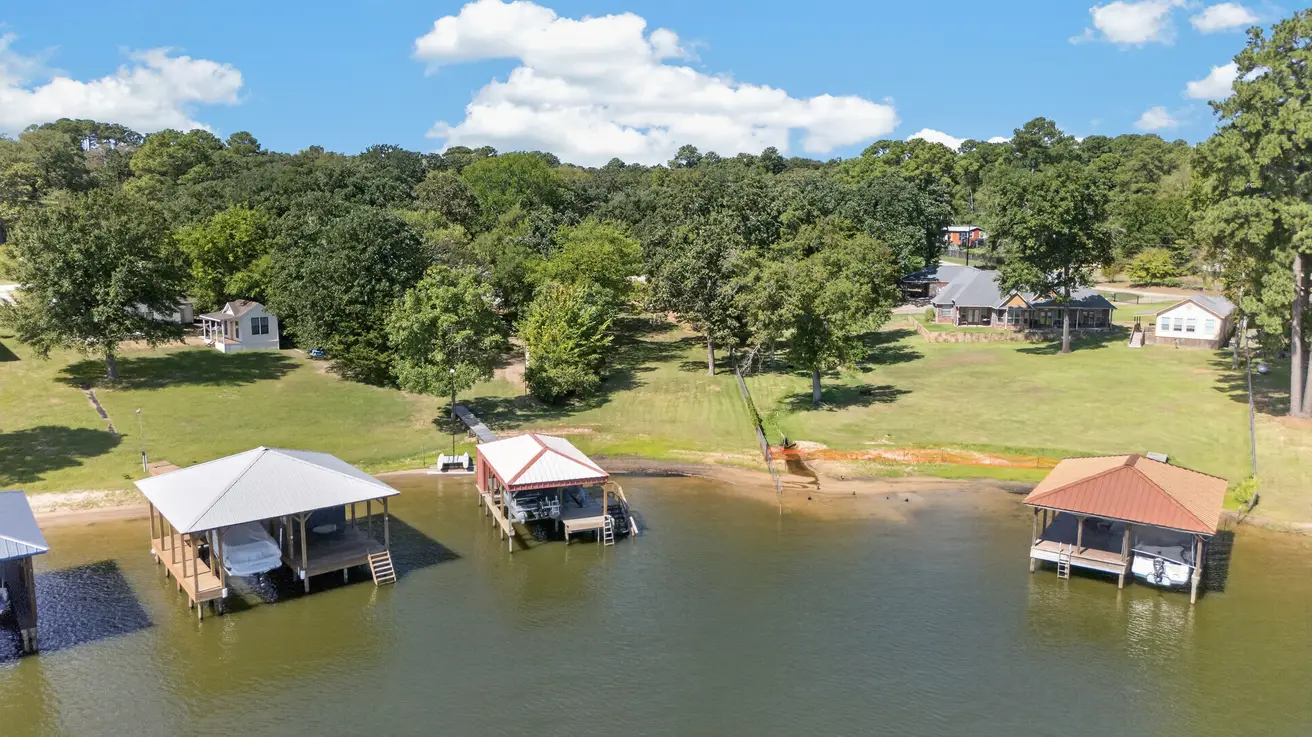 Drone view from Lake Palestine looking back at the Lakeway Harbor shoreline near 22693 Creekwood Dr in Flint TX, with neighboring boathouses and wooded lots.