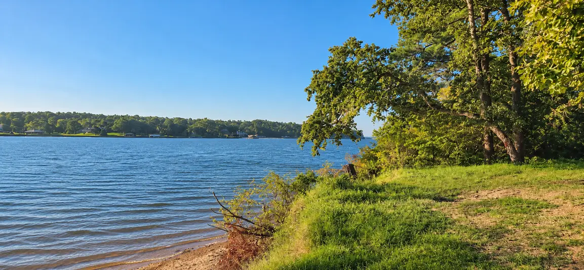 The grassy shoreline at the Lakeway Harbor neighborhood park looking across Lake Palestine.