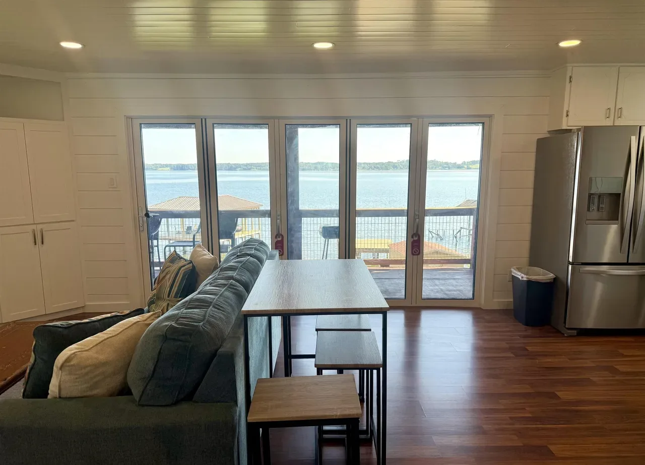 Shiplap walls and a row of glass doors looking out on Lake Palestine from inside the cottage at 7359 E Panorama Dr in Frankston, Texas.