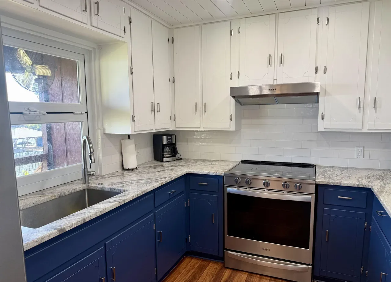Kitchen with navy lower cabinets, white uppers, stone counters and a stainless electric range at 7359 E Panorama Dr, Frankston, Texas.
