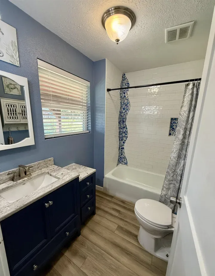 Full bathroom with a navy vanity and a tiled tub and shower in the Brierwood Bay cottage at 7359 E Panorama Dr, Frankston, Texas.