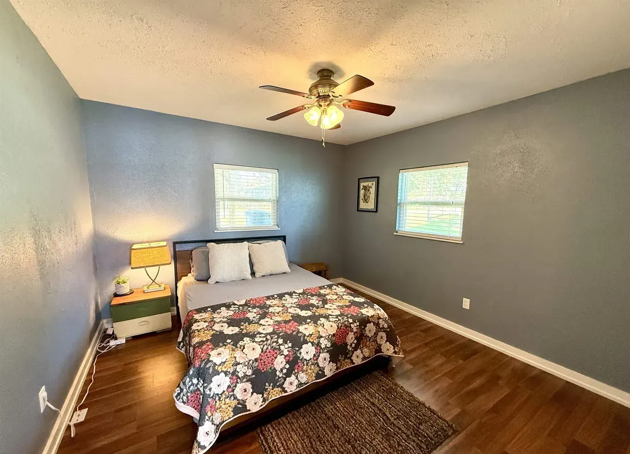 First bedroom with a ceiling fan and two windows in the lakefront cottage at 7359 E Panorama Dr on Lake Palestine.