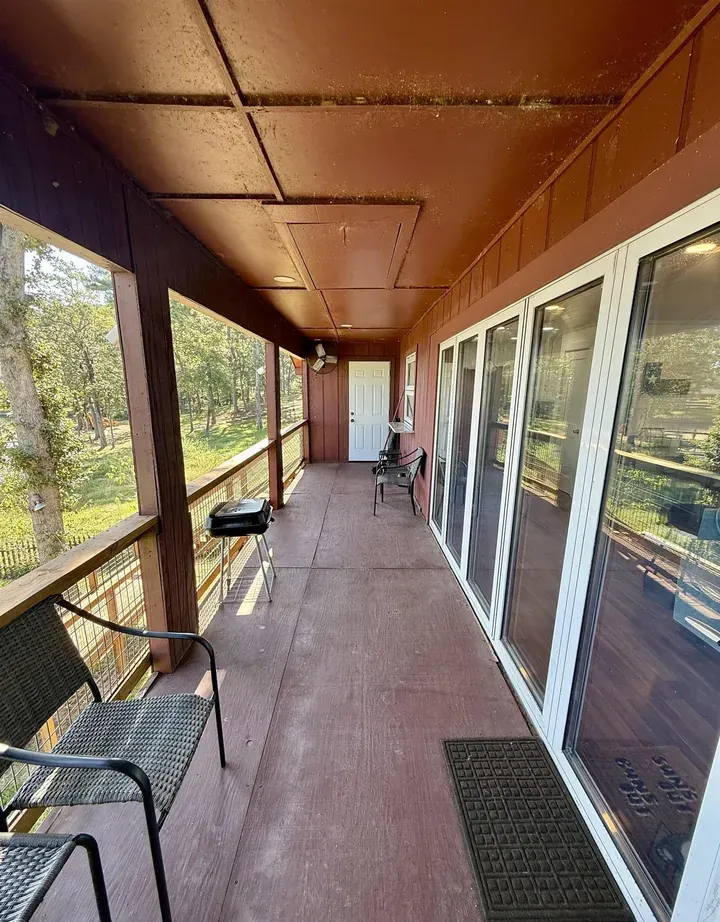 The covered back porch at 7359 E Panorama Dr, a full story above the yard with a wire-mesh railing, looking out over Lake Palestine.